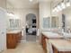 Dual sink bathroom with wood cabinets, marble countertop, and an archway to the Primary bedroom at 1102 Buffalo Ridge Rd, Castle Pines, CO 80108
