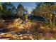 Landscaped backyard with a charming rock waterfall feature and pond, enhanced by lighting at 1102 Buffalo Ridge Rd, Castle Pines, CO 80108