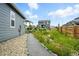 Gravel pathway leading to a beautifully landscaped backyard with a view of neighboring homes at 5417 Riverbend Ave, Firestone, CO 80504