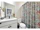 Bright bathroom featuring a floral shower curtain, white vanity with modern fixtures and natural light at 5417 Riverbend Ave, Firestone, CO 80504