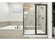 Spacious bathroom with tub, glass shower featuring black trim, and tiled walls and floor at 5417 Riverbend Ave, Firestone, CO 80504