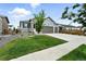 Two-story home with a three-car garage, stone accents, a well-manicured lawn, and lush landscaping at 5417 Riverbend Ave, Firestone, CO 80504