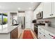 Kitchen featuring stainless steel appliances, an island with modern sink, and white cabinets at 5417 Riverbend Ave, Firestone, CO 80504