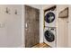 Close-up of a stacked washer and dryer in a laundry area with a modern door and coat hooks at 740 N Sherman St # 107, Denver, CO 80203