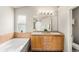 Bathroom featuring double sinks, a large mirror, and a bathtub with tiled surround at 3542 W 125Th Dr, Broomfield, CO 80020