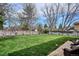 Spacious backyard with lush green lawn, mature trees, and a wood fence perimeter at 8029 W Hoover Pl, Littleton, CO 80123