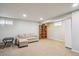 A finished basement space featuring neutral carpet, a sofa, bookshelf, and overhead lighting at 8029 W Hoover Pl, Littleton, CO 80123
