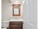 This charming bathroom features a wooden framed mirror, updated vanity, and a neutral color palette at 8029 W Hoover Pl, Littleton, CO 80123