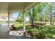 Inviting covered backyard porch with lush greenery, mature trees, and multiple garden beds at 8184 S Ireland Way, Aurora, CO 80016