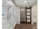 Luxurious bathroom with a frameless glass shower and sliding barn door at 8184 S Ireland Way, Aurora, CO 80016