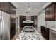 Modern kitchen with stainless steel appliances, dark wood cabinets, and a marble island with cooktop at 8184 S Ireland Way, Aurora, CO 80016