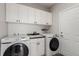 Bright laundry room with white cabinets, modern washer and dryer, and stylish tile flooring at 8184 S Ireland Way, Aurora, CO 80016