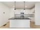 Modern kitchen with white cabinets, granite island, and LVP flooring at 20690 E 58Th Ave, Aurora, CO 80019