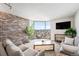 Bright living room featuring brick accent wall, large windows, and comfortable seating area with views of the city skyline at 1625 Larimer St # 2501, Denver, CO 80202