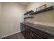 Bar area with dark cabinets, granite counters, and floating shelves at 11828 Churchfield St, Parker, CO 80134