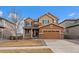 Two-story home with brown siding, a two-car garage, and a covered porch on a sunny day at 11828 Churchfield St, Parker, CO 80134