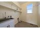 Well-lit laundry room with stainless steel sink, shelving, and tile flooring at 11828 Churchfield St, Parker, CO 80134