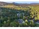 Areal shot showcases a modern home surrounded by dense trees with a pool in the backyard and mountain views at 1298 Meadow View Dr, Evergreen, CO 80439