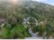 Elevated view capturing a luxury home on a wooded lot, surrounded by lush greenery, with a long driveway at 1298 Meadow View Dr, Evergreen, CO 80439