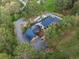 An aerial view showing a unique home design with a blue roof and well-maintained grounds surrounded by dense trees at 1298 Meadow View Dr, Evergreen, CO 80439