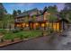 Two-story home with black metal roof, balconies, green lawn, and manicured landscaping at 1298 Meadow View Dr, Evergreen, CO 80439