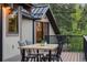 Outdoor dining on a wood patio with seating for four, with beautiful wood design and black metal railing at 1298 Meadow View Dr, Evergreen, CO 80439