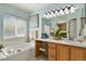 Relaxing bathroom with a soaking tub, vanity area, and a large window at 9860 Burberry Way, Highlands Ranch, CO 80129