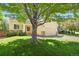 Charming yellow home with stone accents, a well-manicured lawn, and a tree in the front yard at 9860 Burberry Way, Highlands Ranch, CO 80129
