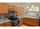 Bright kitchen featuring stainless steel appliances, light wood cabinets, and a breakfast bar opening to the living area at 9860 Burberry Way, Highlands Ranch, CO 80129