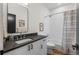 Well-lit bathroom featuring a dark countertop, white cabinetry, and a modern shower with curtain at 3285 Lawrence St, Denver, CO 80205