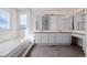 Bright bathroom featuring a double vanity, a soaking tub next to a window and tiled floors at 9275 Erminedale Dr, Lone Tree, CO 80124