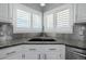 Close-up of a kitchen sink with double windows, white cabinets, and modern faucet at 9275 Erminedale Dr, Lone Tree, CO 80124