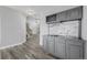 Stylish wet bar with gray cabinetry, wine rack, backsplash, sink, and views to the foyer with wood staircase at 9275 Erminedale Dr, Lone Tree, CO 80124