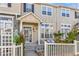 Charming two-story townhome with a covered entry, white picket fence, and well-manicured landscaping at 1465 Red Cliff Way, Castle Rock, CO 80109