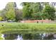 Scenic view of a pond reflecting a house and trees, with a green space and picnic table nearby at 7150 S Curtice St, Littleton, CO 80120