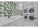 Modern laundry room features side by side washer and dryer, marble countertops, and floral wallpaper at 1265 S Gaylord St, Denver, CO 80210
