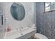 Unique powder room showcasing blue wallpaper, a modern round mirror, and a sleek white sink at 1265 S Gaylord St, Denver, CO 80210