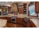 Kitchen featuring custom cabinets, a stone range hood, stainless steel appliances, and a copper sink at 8871 Aspen Leaf Ct, Littleton, CO 80125