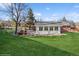 Exterior view of the home with a well-maintained lawn, back patio, and sunroom at 11600 W 31St Pl, Lakewood, CO 80215