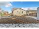 A view of the home's backyard, featuring a large grassy area and detached garage at 740 Fulton Ave, Fort Lupton, CO 80621