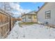 Side yard of the property with a wooden fence and snowy ground at 740 Fulton Ave, Fort Lupton, CO 80621