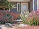 Close up of the home's front entrance surrounded by beautiful landscaping and colorful flowers at 2155 S Deframe St, Lakewood, CO 80228