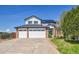 Beautiful two-story home with a three-car garage, lush lawn, brick accents, and solar panels under a bright blue sky at 12408 W 83Rd Ave, Arvada, CO 80005