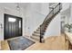 Elegant foyer with a black front door, a curved staircase, and beautiful hardwood floors with an area rug at 12408 W 83Rd Ave, Arvada, CO 80005