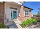 Inviting front porch with brick pillar, landscaped garden, door with screen, and a glimpse into the home at 12408 W 83Rd Ave, Arvada, CO 80005