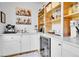 Pantry featuring white cabinets, open wood shelving, and stainless steel beverage fridge at 12408 W 83Rd Ave, Arvada, CO 80005