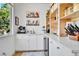 Pantry featuring white cabinets, open wood shelving, and stainless steel beverage fridge at 12408 W 83Rd Ave, Arvada, CO 80005