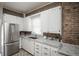 Contemporary kitchen boasting white cabinetry, brick walls, granite countertops, and stainless steel appliances at 136 W Maple Ave, Denver, CO 80223