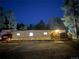 Exterior view of brick home featuring manicured yard, privacy fence, and mature trees at night at 34480 County Road 17, Elizabeth, CO 80107