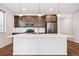 Modern kitchen with stainless steel appliances, dark cabinetry, a white backsplash, and a large island at 27862 E 9Th Dr, Aurora, CO 80018